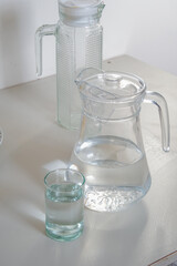 Close-up of a jug and a glass filled with clear water on a white kitchen surface