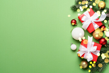 Christmas gift box and holiday decorations at green background.