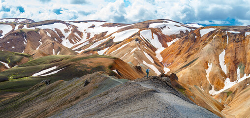 Iceland Travel -View from the top of Bl&aacute;hnj&uacute;kur mountain with a senior man taking a photograph of the scenic views of Landmannalaugar Fjallabak Nature Reserve.