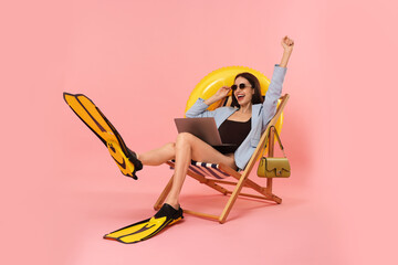 Businesswoman with laptop and flippers in deck chair on pink background © New Africa