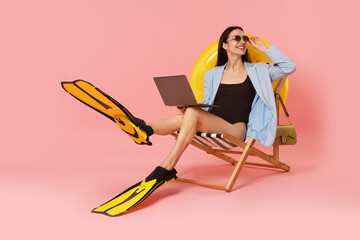 Businesswoman with laptop and flippers in deck chair on pink background © New Africa