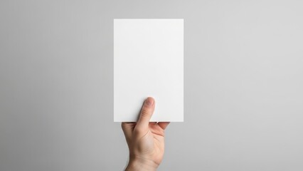 Hand holding a blank white card against a simple grey background
