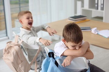 Boy getting bullied by his classmate in school, selective focus