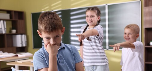 Boy getting bullied by his classmates in school, selective focus