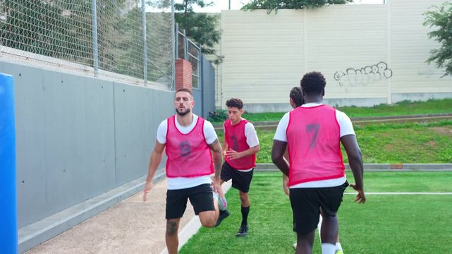 Young male athletes performing warm up drills on a soccer field. Team of football players exercising and preparing for a match on the pitch