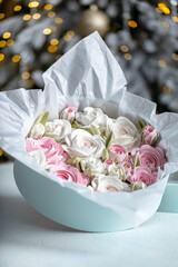 Beautiful arrangement of pink and white roses in a light blue gift box, surrounded by festive decorations, creating a charming holiday atmosphere with soft lighting