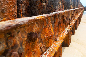 Rough, distressed surface of a forgotten seaside breakwater with vibrant corrosion and decay due to saltwater exposure.