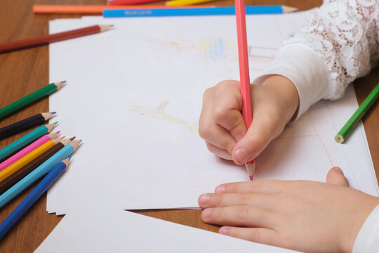 Young kid creating simple drawing with pink pencil on large sheet