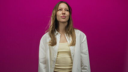 Woman in white shirt and cream tank top smiles and looks up in magenta studio; playful warm...