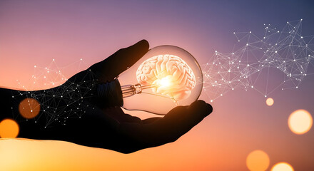 Silhouette of a Hand Holding a Light Bulb with a Brain Inside Symbolizing Innovation and Ideas at Sunset.