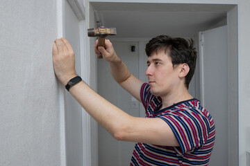 A young man hammering a nail in his home. Home improvement and renovation