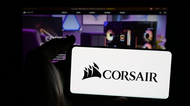 Stuttgart, Germany - 11-27-2025: Person holding mobile phone with logo of computer hardware company Corsair Gaming Inc. on screen in front of web page. Focus on phone display.