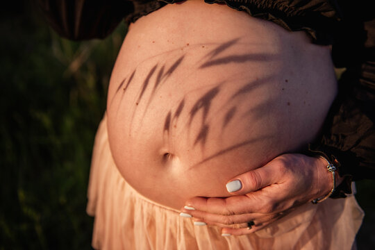 Pregnant woman cradling belly in nature setting