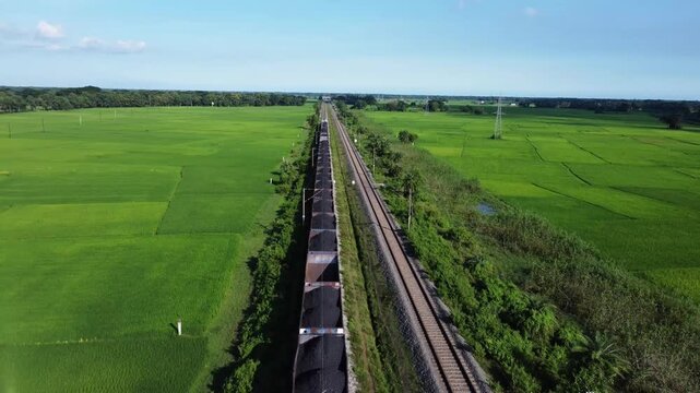 Coal transport on railway in middle of the rice field. Indian coal transportation.