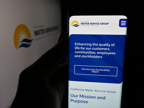 Stuttgart, Germany - 11-27-2025: Person holding smartphone with web page of US company California Water Service Group on screen in front of logo. Focus on center of phone display.