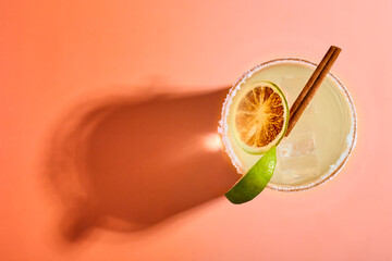 Top view of a margarita cocktail in a salt-rimmed glass with ice, garnished with a lime slice,...
