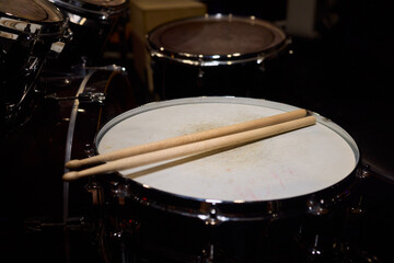 Drummer hands striking snare drum with sticks, captured midperformance showing motion blur, textured drumhead, casual stage clothing and focused groove driving live club energy