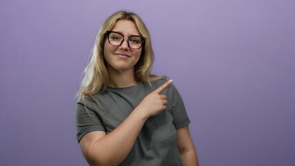 Woman pointing with both hands over isolated purple background, wearing glasses and a gray shirt,...