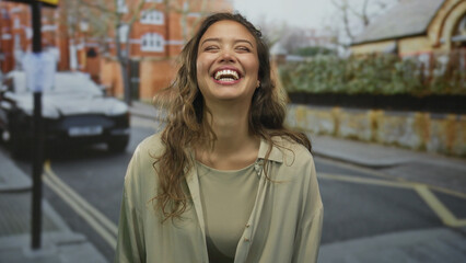Fototapeta premium Woman smiling on a city street, exuding happiness and confidence with vibrant urban surroundings, showcasing casual fashion in a lively outdoor setting.