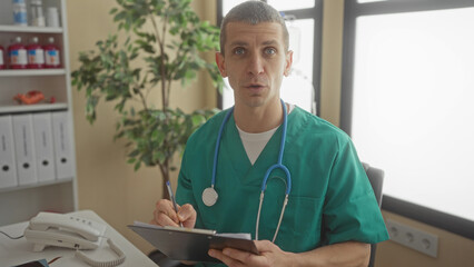 Man doctor in clinic with stethoscope writing notes on clipboard at hospital office surrounded by medical equipment showcasing a professional healthcare environment.