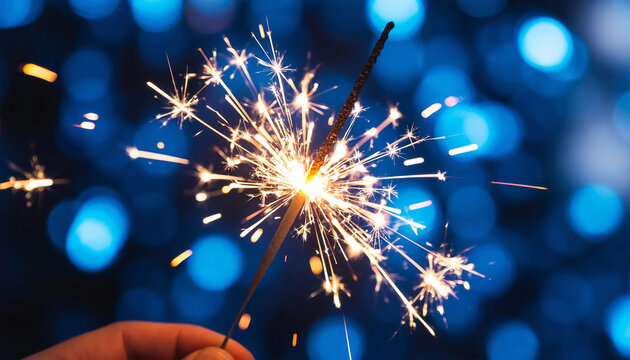 Christmas and New Year party sparkler in hand on blue bokeh background