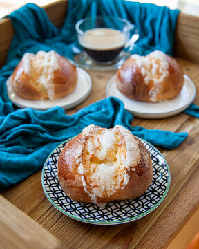Freshly baked brioche buns with coffee on a wooden tray