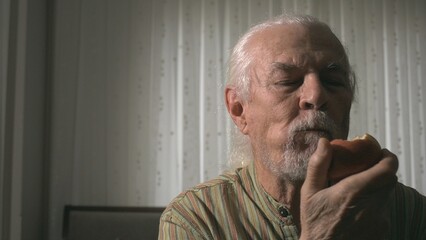 The man is seen biting into a bright red apple in his hand with great pleasure and appetite, and the sincere happiness and pleasure on his face are clearly visible.