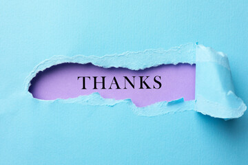 Thank You card with word on violet background, view through torn light blue paper