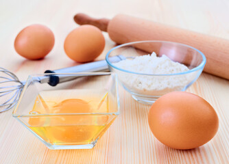 Baking ingredients with eggs and flour on wooden table