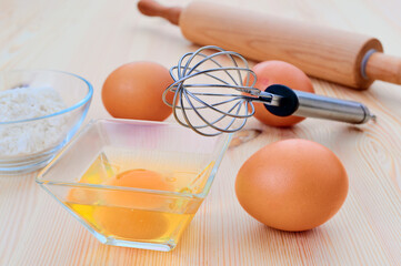 Baking essentials with eggs and flour on wooden table