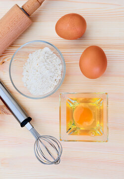 Baking essentials with eggs and flour on wood surface