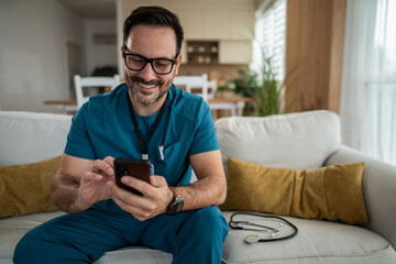 Male doctor relaxing home while using smartphone