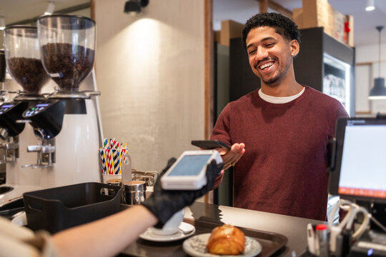 Customer paying at cafe counter with croissant