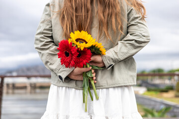 Woman holding colorful flowers in serene outdoor park