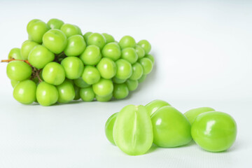Fresh green grapes on white surface with close-up view