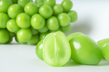 Fresh green grapes on white background with halved fruit detail