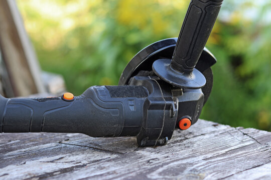 Cordless angle grinder on a wooden table. Tool for repair and construction. Cordless angle grinder close-up. Tool in the country