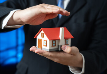 A man protects a house in his hands. Home insurance. Affordable housing. Property safety and family security. Mortgage services, real estate consulting and financial protection