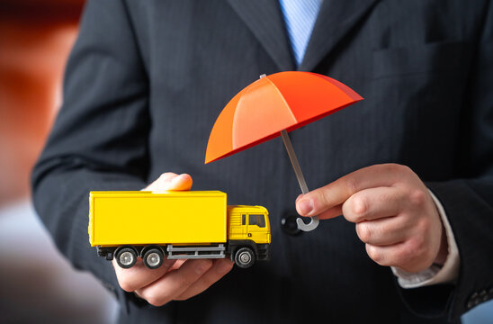 Fototapeta A businessman holds an umbrella over a truck. Concept for insurance of transportation and cargo. Logistics protection, supply chain risk management. Transport industry coverage and insurance promotion