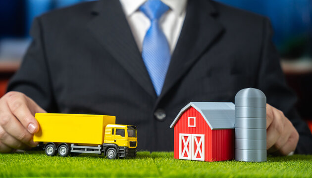 A businessman drives a truck to a farm. Establishing logistics in retail and agricultural production. Supply chain integration and rural delivery. Agribusiness, retail logistics and food distribution.