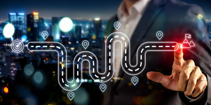 Businessman's hand activates digital roadmap to success with city lights background