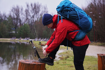 a man ties the laces of his trekking boots while hiking in the forest