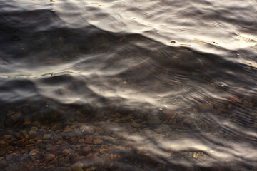 The low evening sun softly illuminates the waves and rocky bottom
