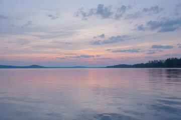 Fototapeta premium Serene lake at sunset with pastel colored clouds reflecting on calm water surface