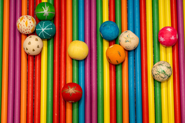 Abstract background of vertical colored wooden sticks and scattered round beads. Bright rainbow colors texture