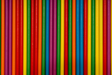 Full frame background of arranged vertical wooden sticks in rainbow colors. Abstract striped pattern texture