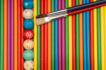 Top view of two paint brushes lying on a texture of vertical colorful wooden sticks. Art and craft concept
