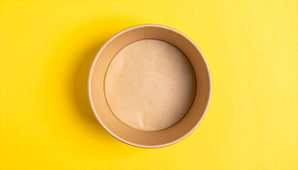 Eco-friendly craft paper bowl for food on yellow background, biodegradable disposable tableware.