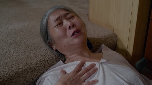 An elderly woman experiencing a medical emergency on the floor Stock Video