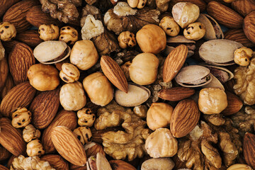Close up background of mixed nuts. Almonds, walnuts, chickpeas, hazelnuts and pistachios. Creative healthy food concept. Raw and organic nuts flat lay. Top view.